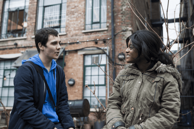 a person and person talking in front of a brick building