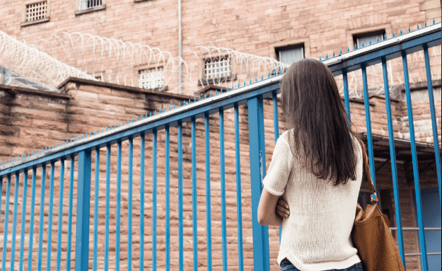 a woman standing next to a prison gate