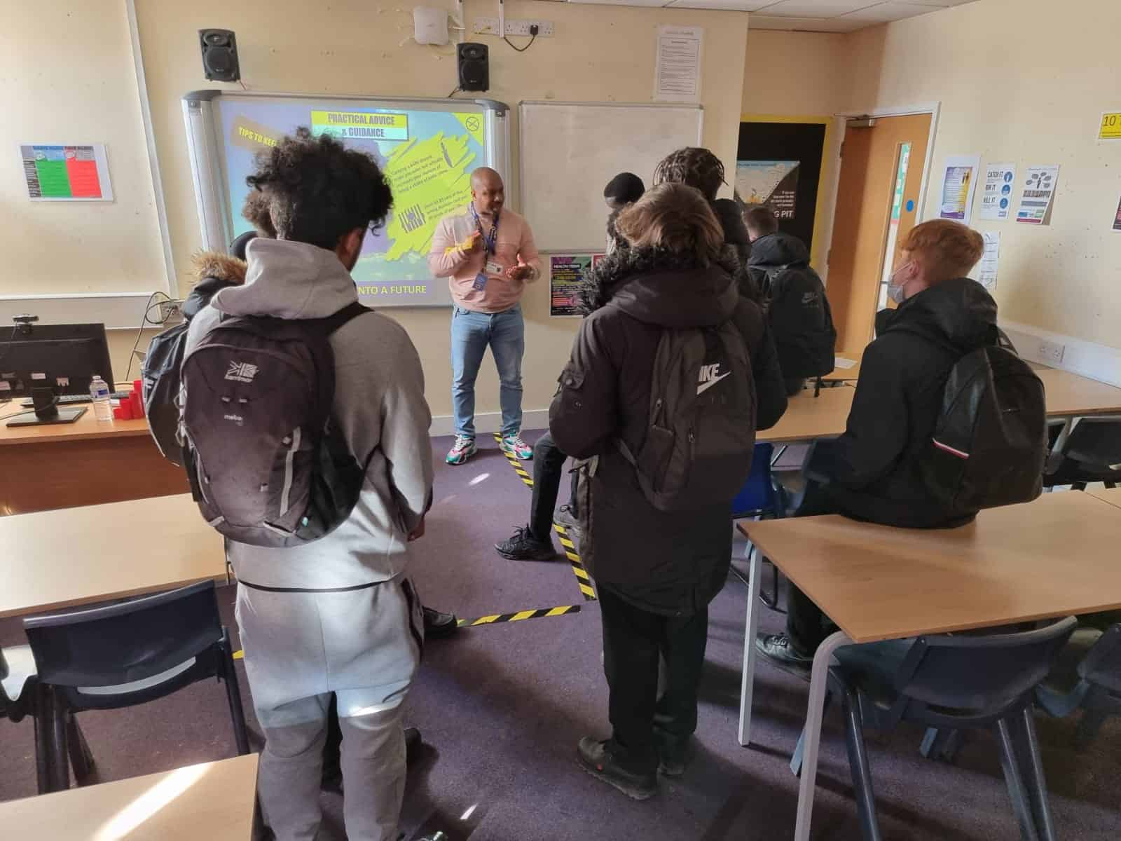 a person standing in front of a group of people in a classroom