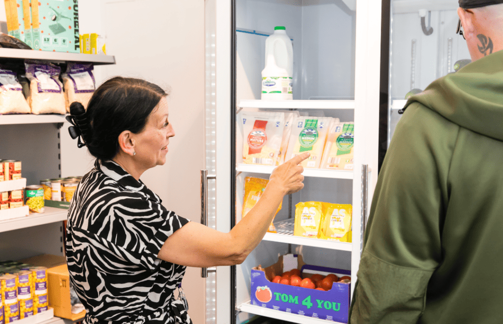 a woman pointing at a refrigerator