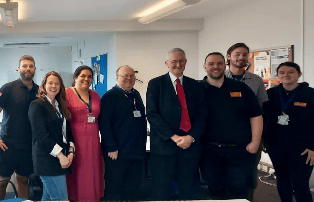 Photograph of St Giles Yorkshire Staff stood smiling in their office with Leeds Central MP Hilary Benn.