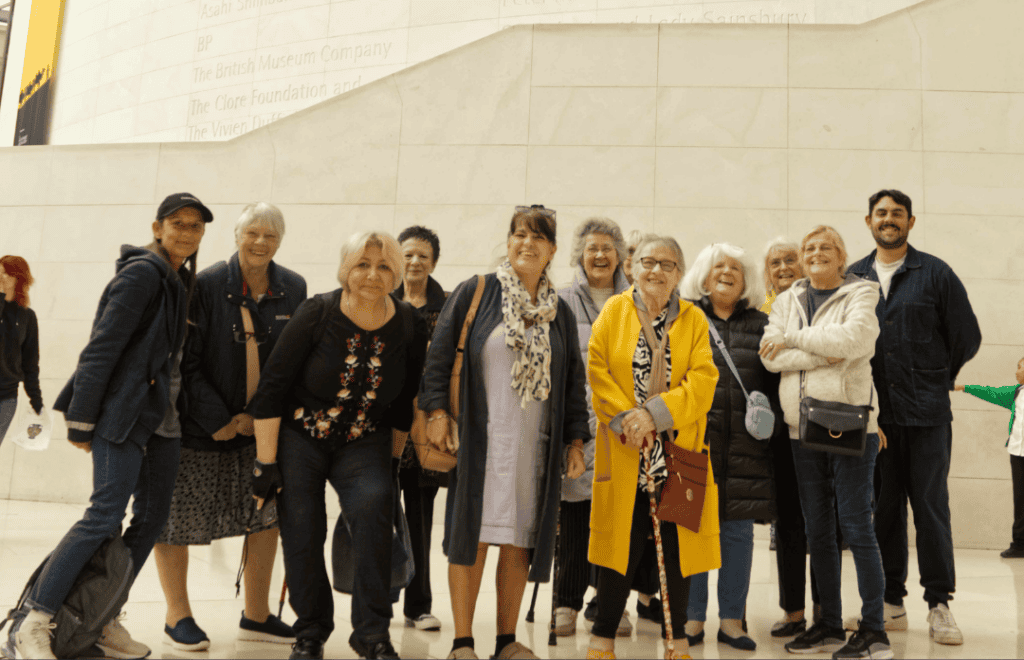 Photograph of a group of people stood in front of a white stone monument at the British Library
