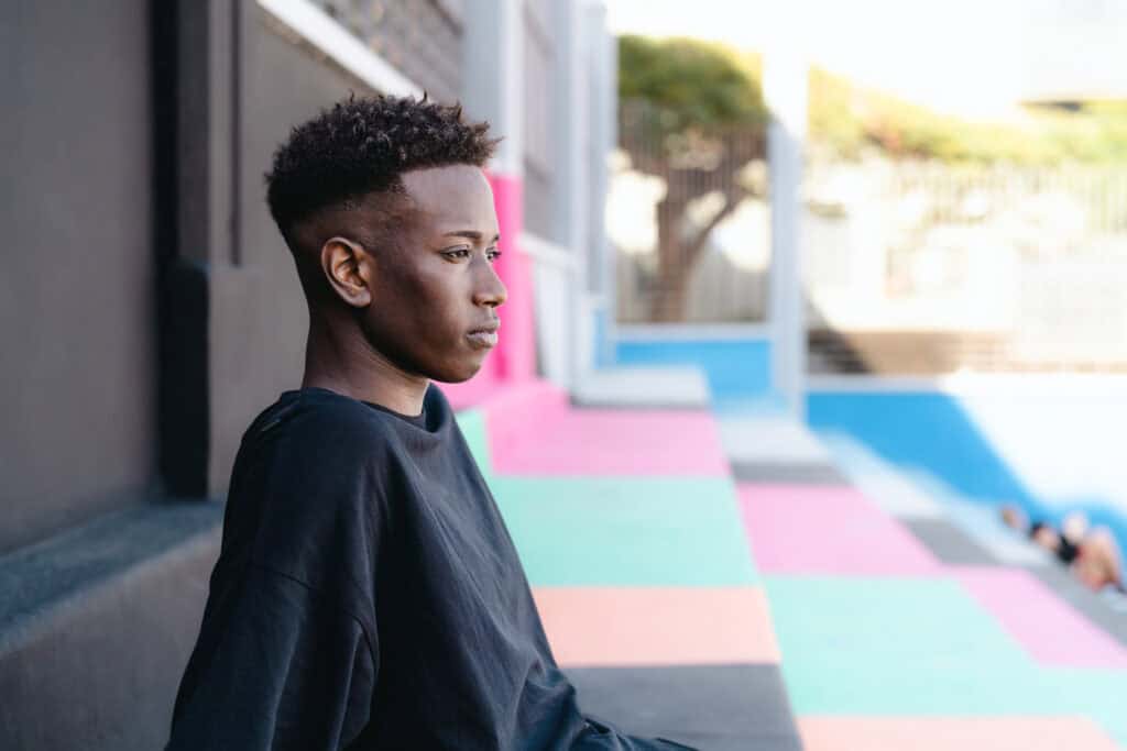Young African teenager sitting on stairs of basketball court