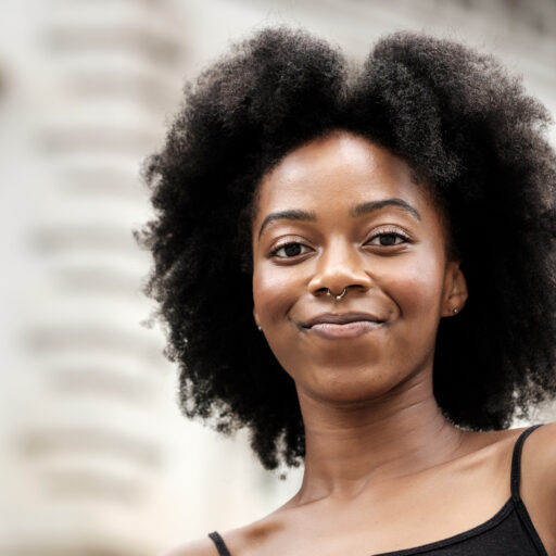 Head shot of happy global majority woman mid 20s in urban setting