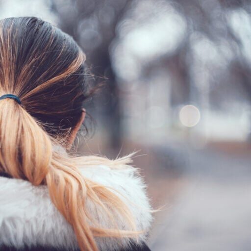 A close-up of a beautiful girl with blonde colored hair held in a ponytail wearing warm winter clothing and is looking away from the camera with copy space on the right.