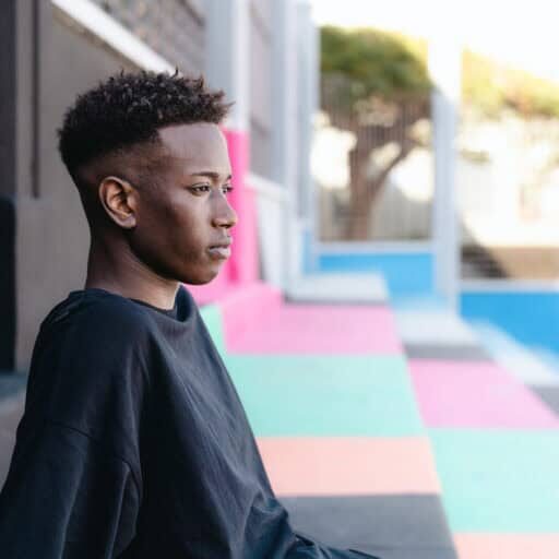 Young African teenager sitting on stairs of basketball court